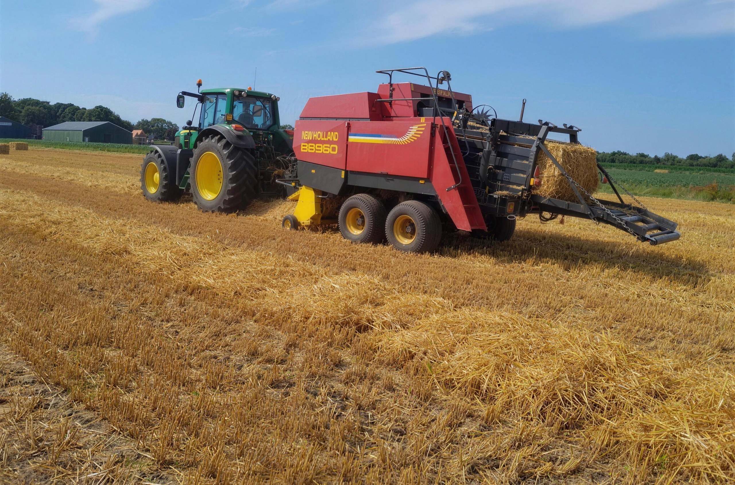 Trekker met New Holland BB960 grootpakpers in het stro