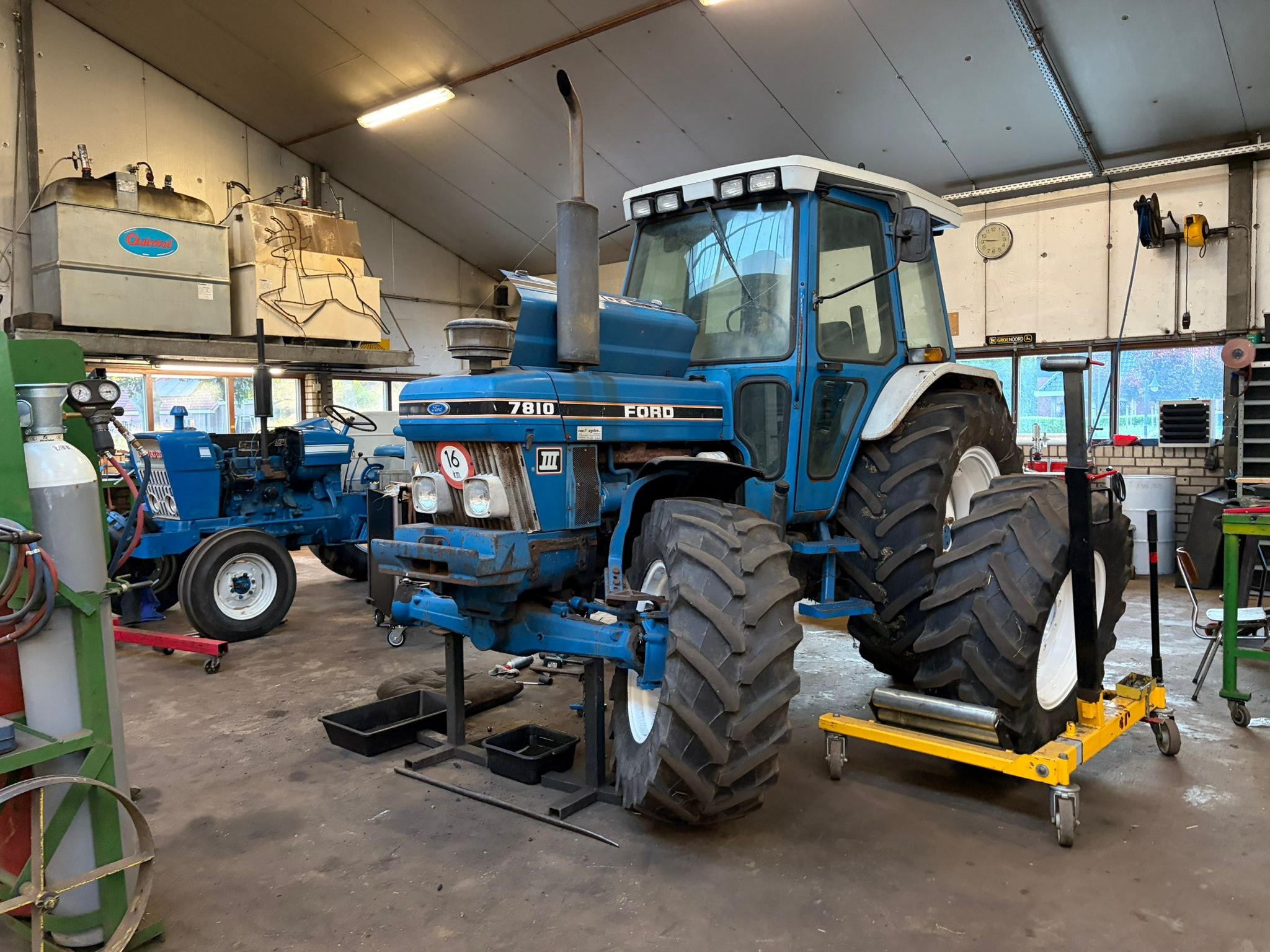 Ford 7810 op stempels in de werkplaats, met de vooras ondersteund