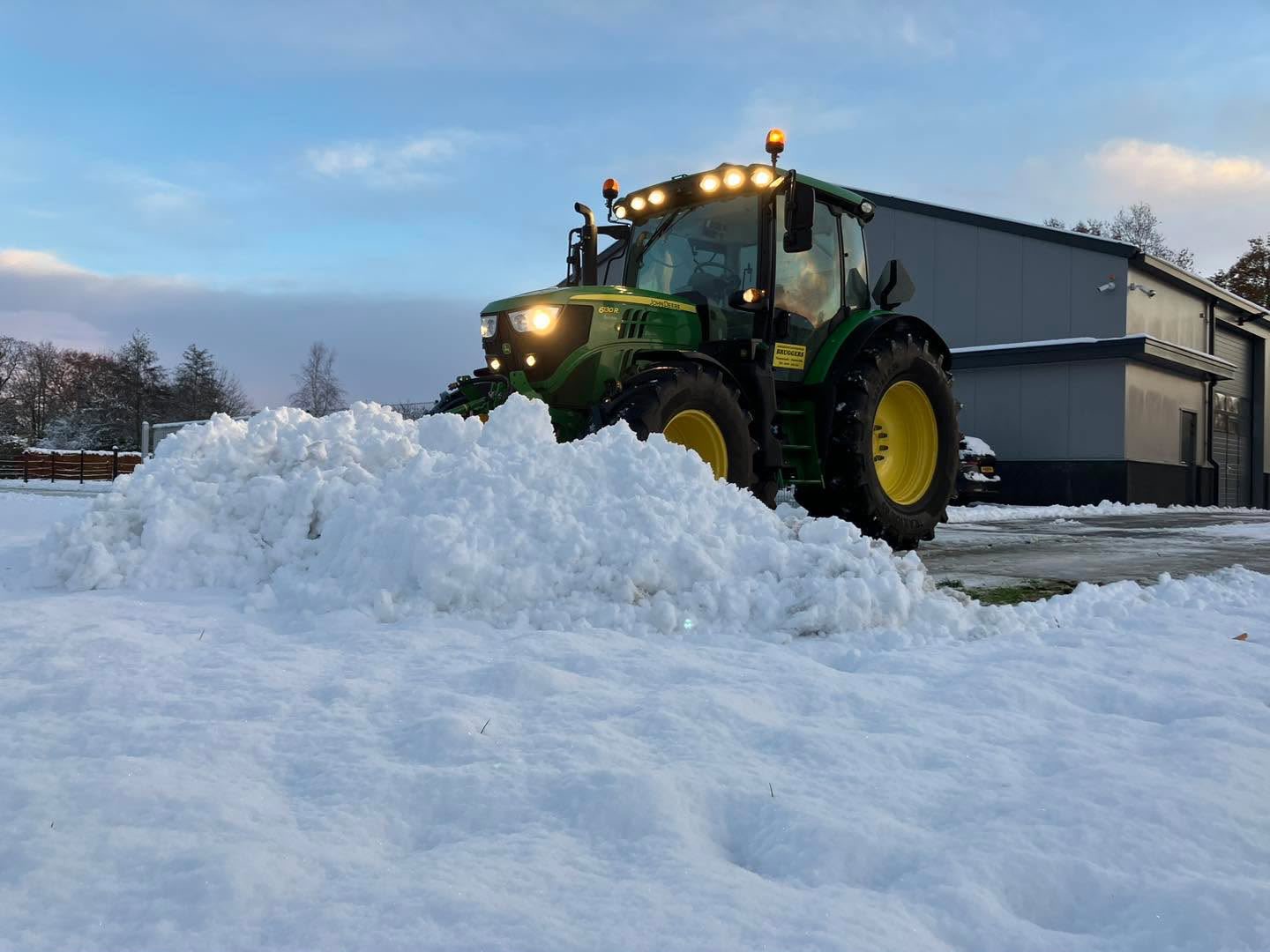 Trekker met sneeuwschuif op een bedrijfsterrein