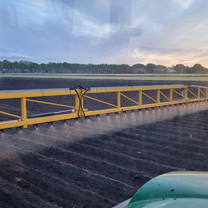 Veldspuit met uitgeklapte boom over het land